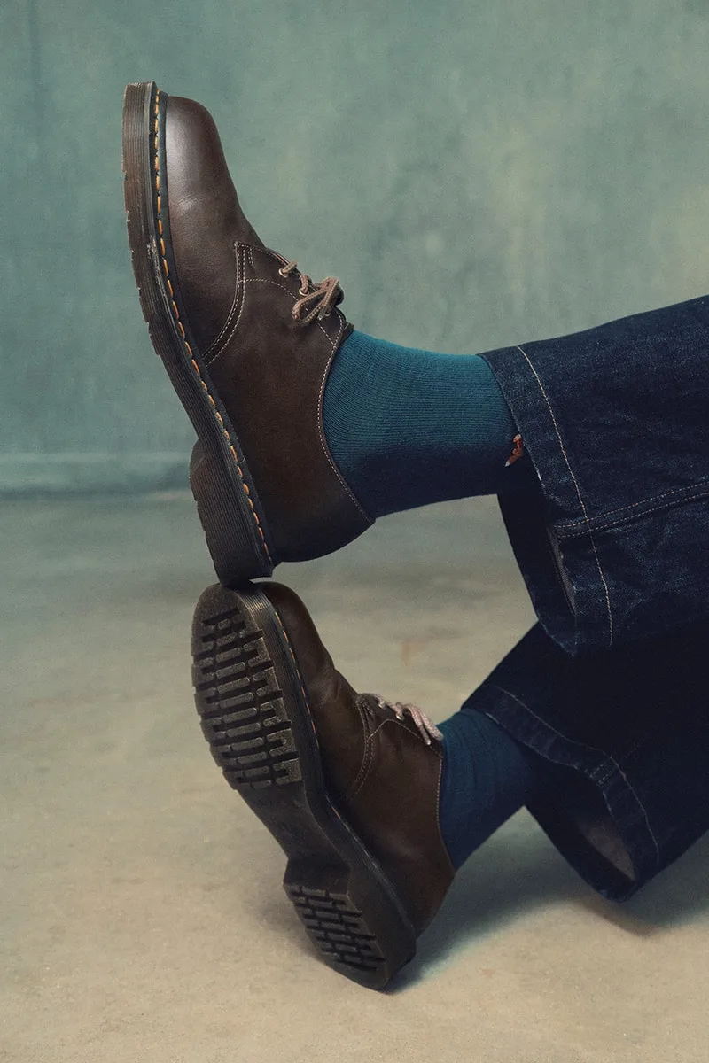 Pantalon en jean, chaussettes bleues, chaussures marron sur fond gris