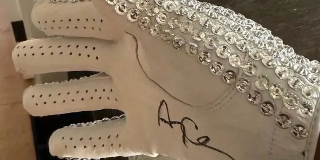 Gant blanc orné de sequins argentés avec une signature noire.