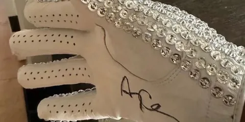 Gant blanc orné de sequins argentés avec une signature noire.