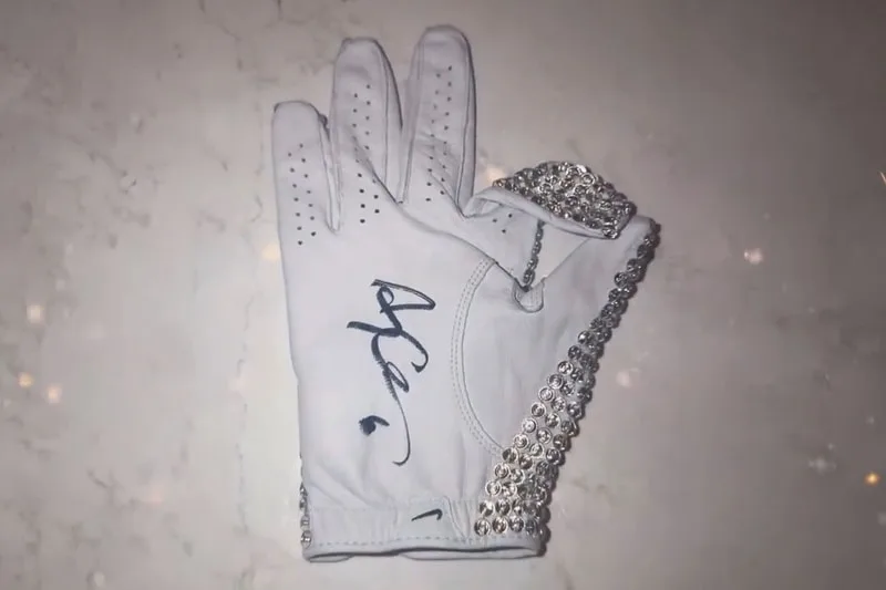 Gant blanc orné de bijoux et signé sur une table.