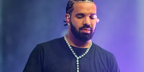 Homme barbu avec tresse et chaîne sur scène.