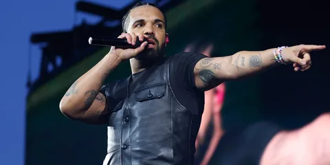 Chanteur sur scène avec micro, portant un gilet noir.