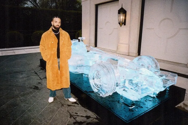 Homme avec manteau devant sculpture de voiture de course en glace.