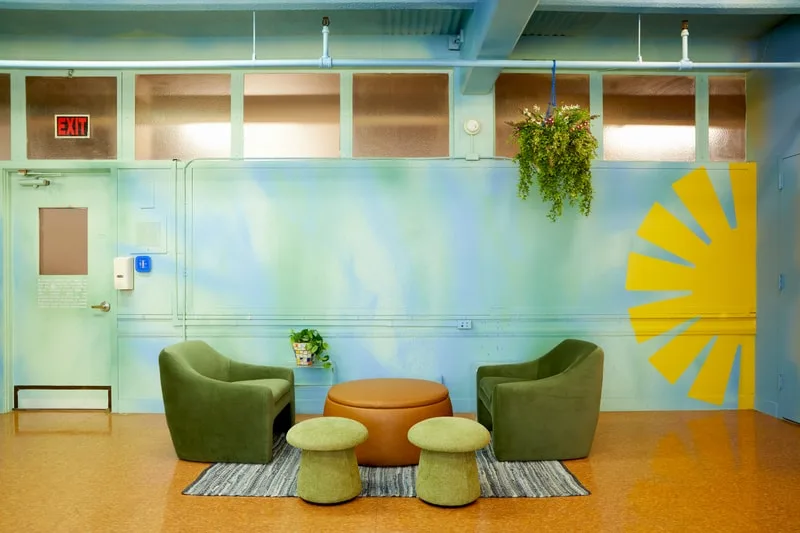 Intérieur moderne avec des fauteuils verts et plantes suspendues.