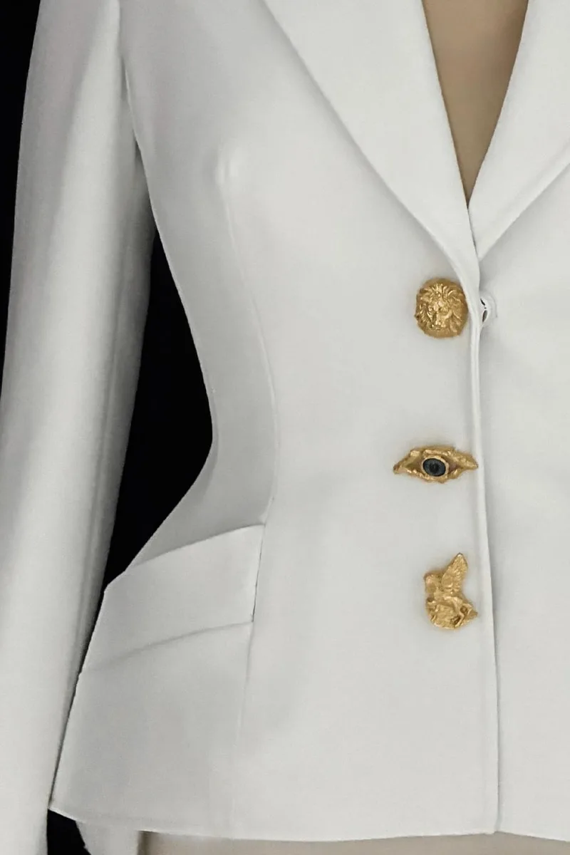 Veste blanche avec boutons dorés décoratifs.