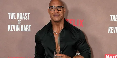Homme en chemise noire avec un verre à la main lors d'un événement.