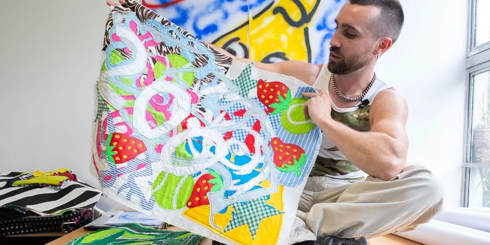 Un homme montrant une pièce d'art textile colorée.
