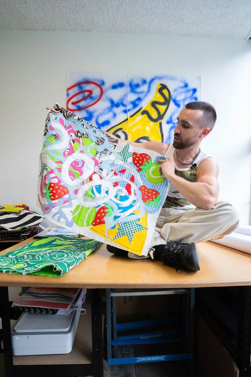 Un homme montre une œuvre d'art colorée sur une table.