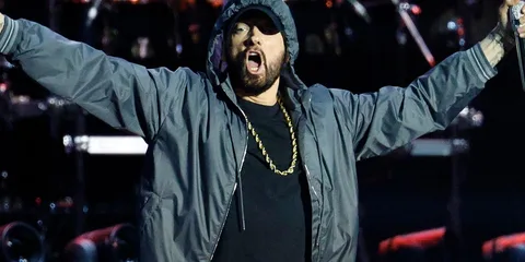 Personne en veste avec capuche sur scène avec micro.