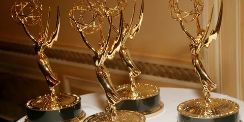 Quatre trophées Emmy dorés sur un fond intérieur élégant.