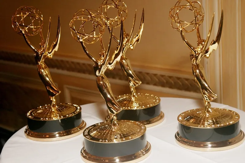 Quatre trophées Emmy dorés sur une table blanche.