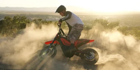 Homme en motocross électrique dans la poussière au coucher du soleil.