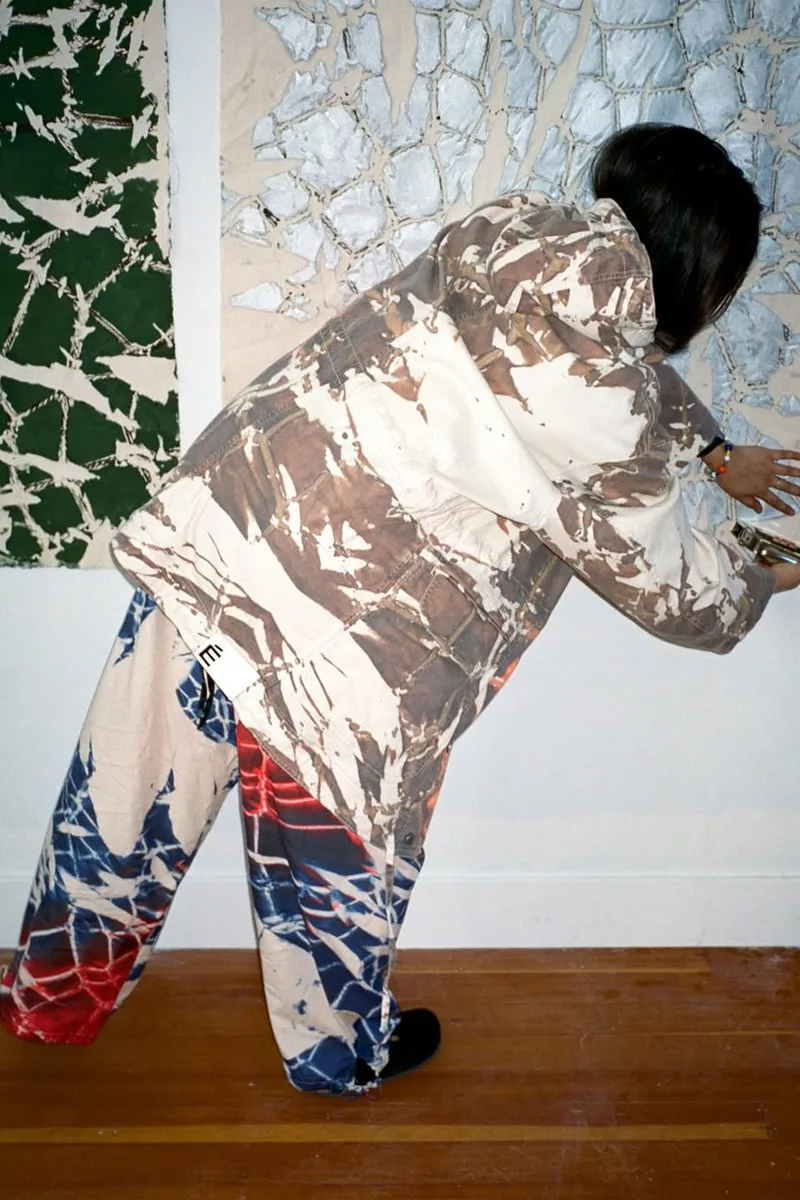 Personne avec vêtements colorés devant une œuvre d'art abstraite.