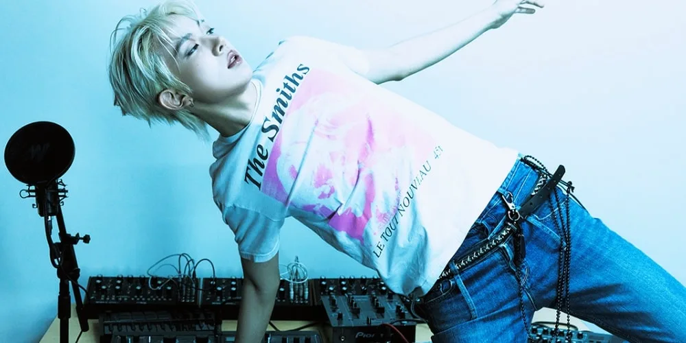Personne en t-shirt avec synthétiseurs et microphone, lumière bleue.