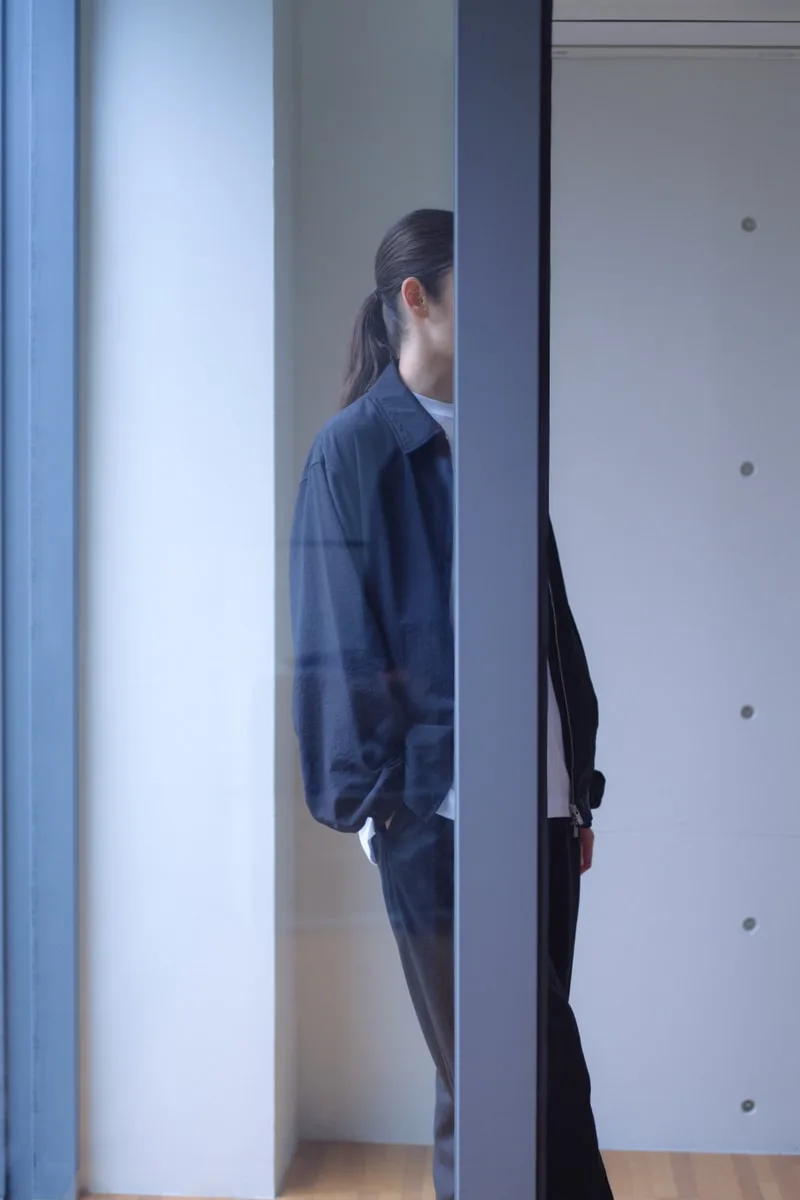 Personne debout à moitié cachée par un mur dans un intérieur moderne.