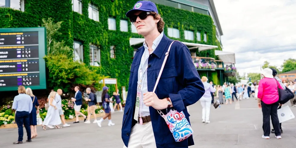 Homme élégant avec un sac coloré, fond de tournoi de tennis.