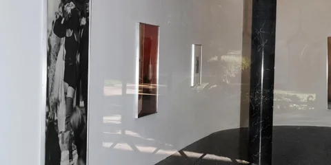 Personne avec appareil photo devant une grande fenêtre arrondie.