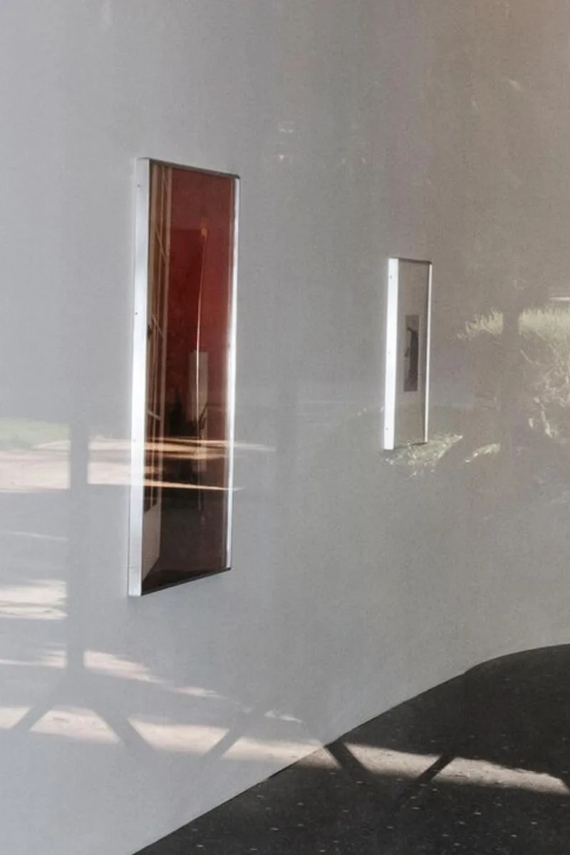 Deux cadres sur un mur courbé avec reflets et ombres visibles.