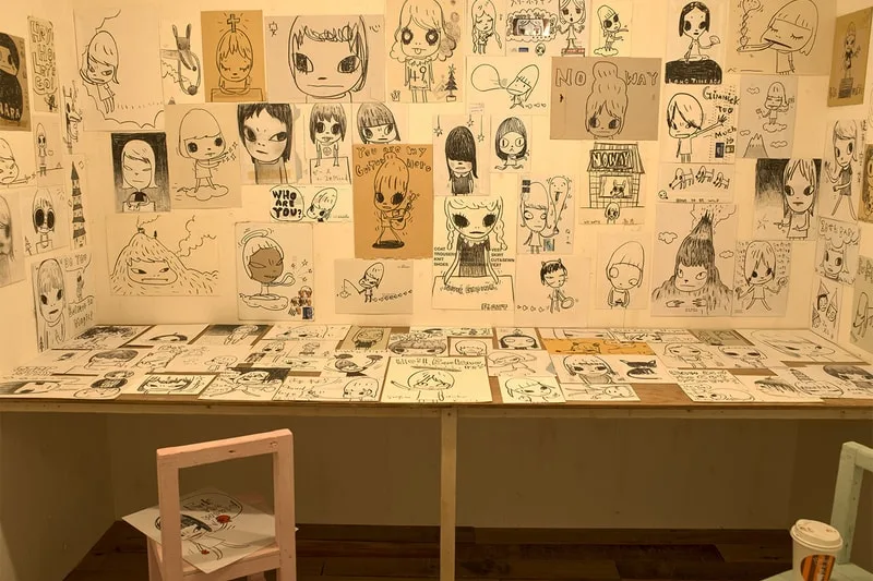 Dessins d'art enfantin sur mur et table, style croquis en noir et blanc.