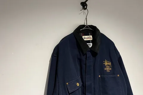 Veste noire accrochée avec logo doré sur le devant.