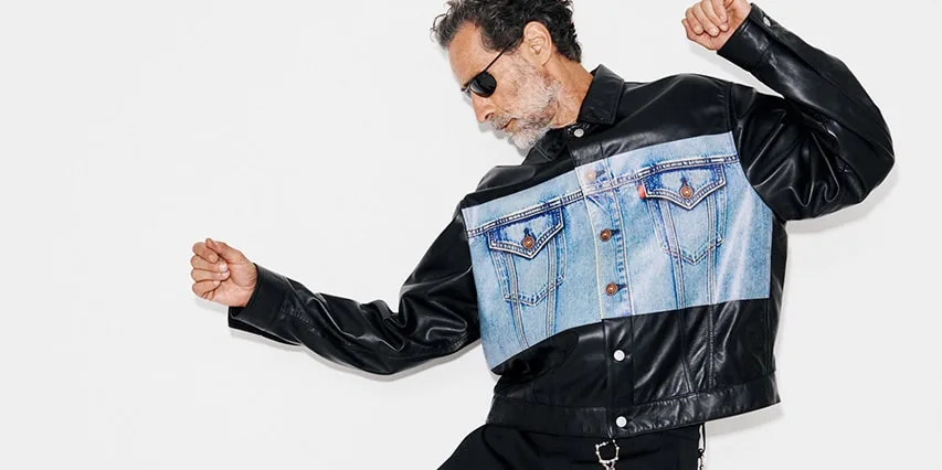 Homme avec veste en cuir et denim, lunettes de soleil, pose dynamique.