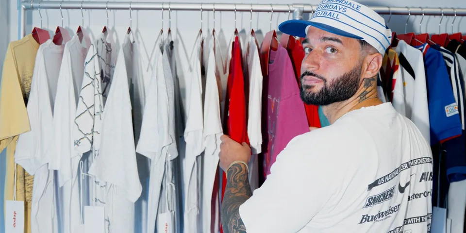 Homme avec casquette examinent des t-shirts sur des cintres.