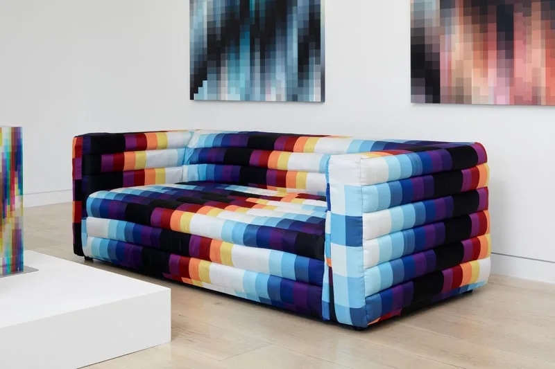 Canapé multicolore avec motifs pixélisés dans une galerie d'art moderne.