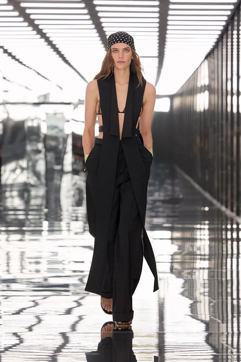 Modèle en tenue noire élégante sur un podium moderne.