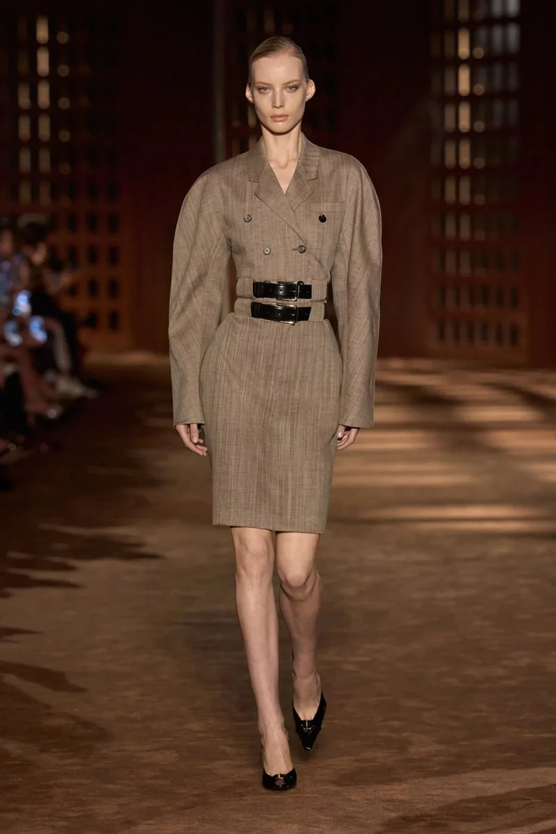 Modèle en robe marron sur le podium d'un défilé de mode.