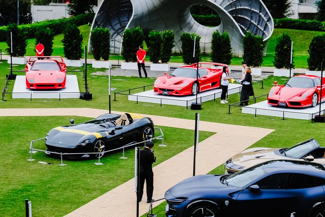 Exposition de voitures de sport rouges et noires sur une pelouse verte.