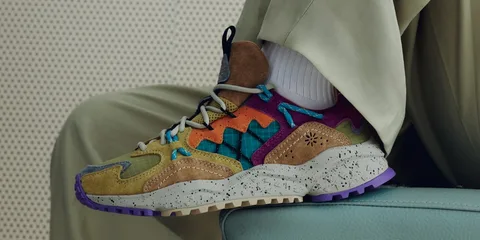 Chaussure colorée avec motif et semelle tachetée, posée sur une surface bleue.