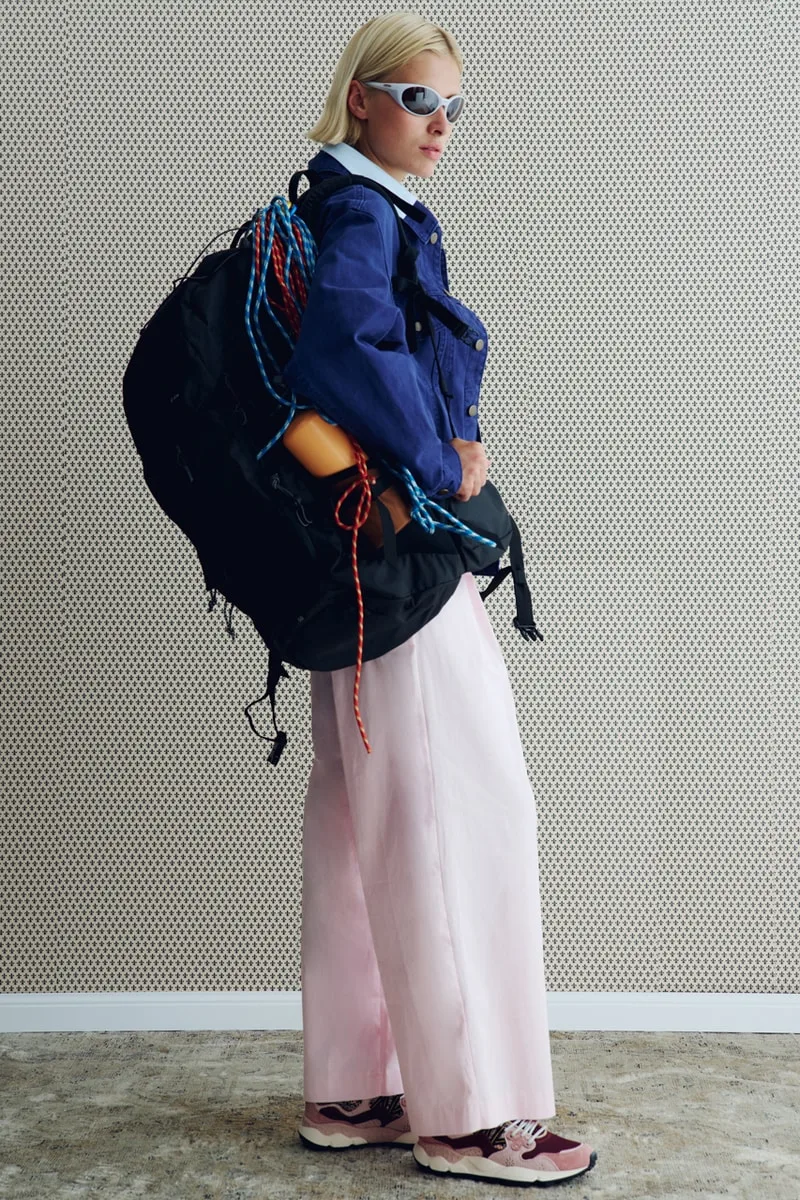 Personne avec lunette de soleil, sac et vêtements colorés, pose intérieure.