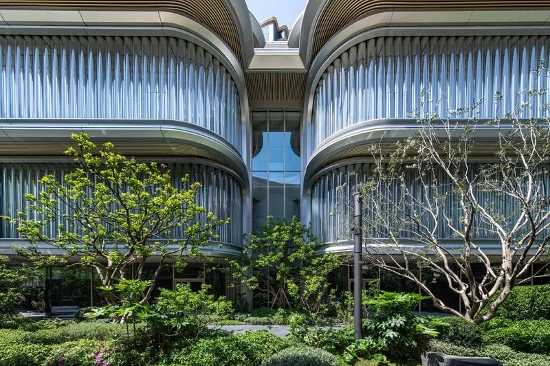 Bâtiment moderne avec des fenêtres courbées et un jardin au premier plan.