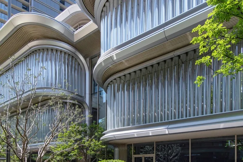 Façades modernes avec fenêtres incurvées et arbres au premier plan.