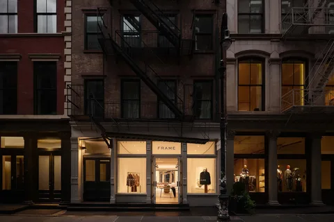 Façade d'une boutique de vêtements éclairée la nuit.