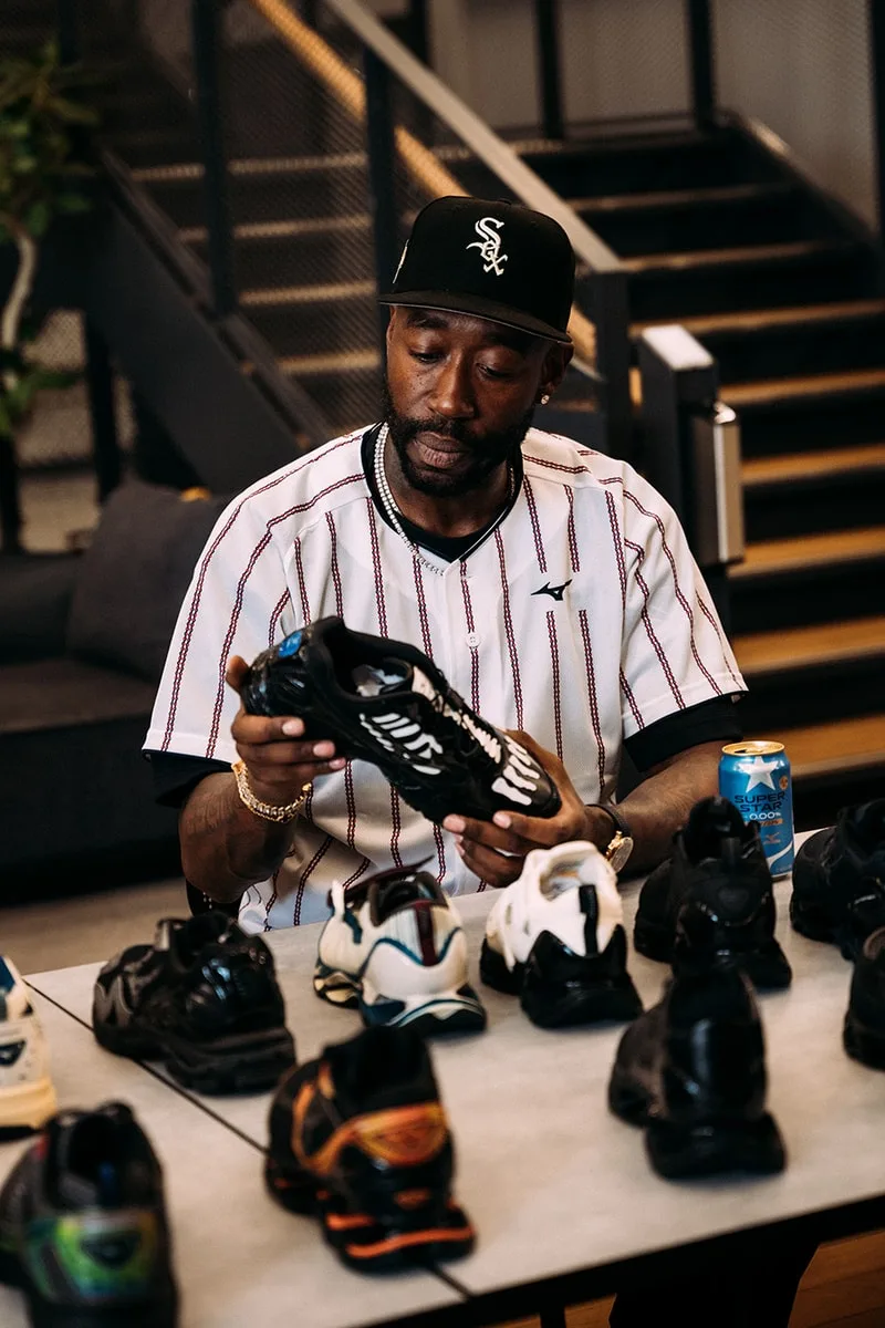 Homme examinant des baskets sur une table avec casquette noire.