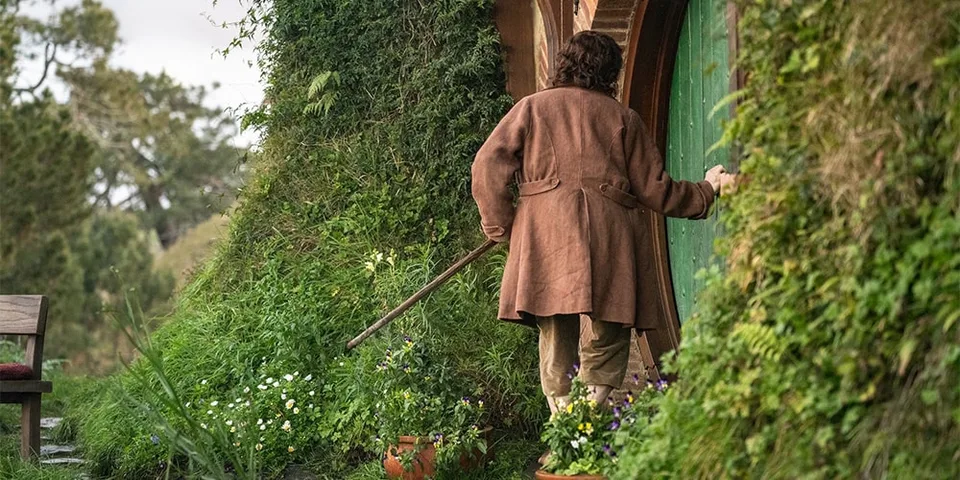 Une personne en manteau brun chez elle dans la nature luxuriante.