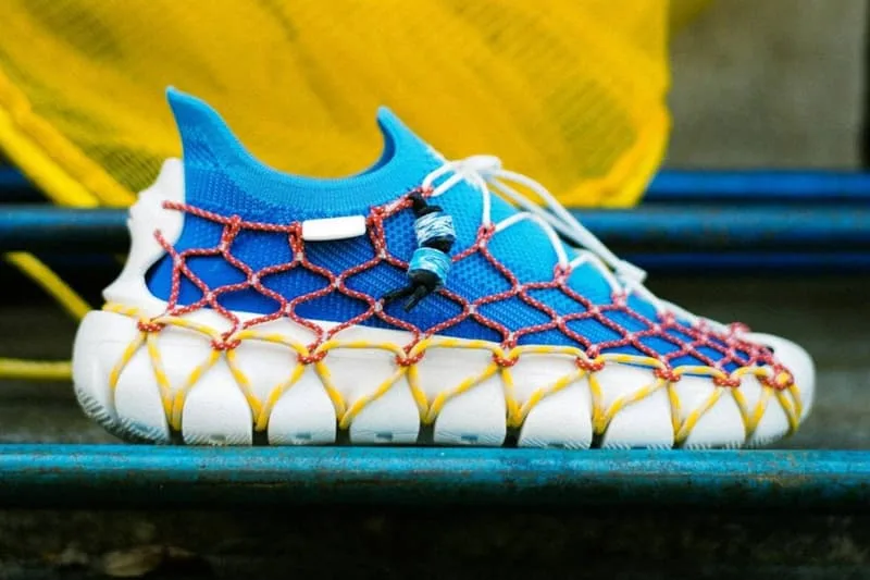 Chaussure bleue et blanche avec filet rouge et jaune, design unique et moderne.