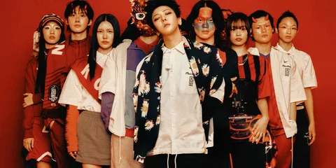 Groupe de personnes avec des vêtements de style varié devant un fond rouge.