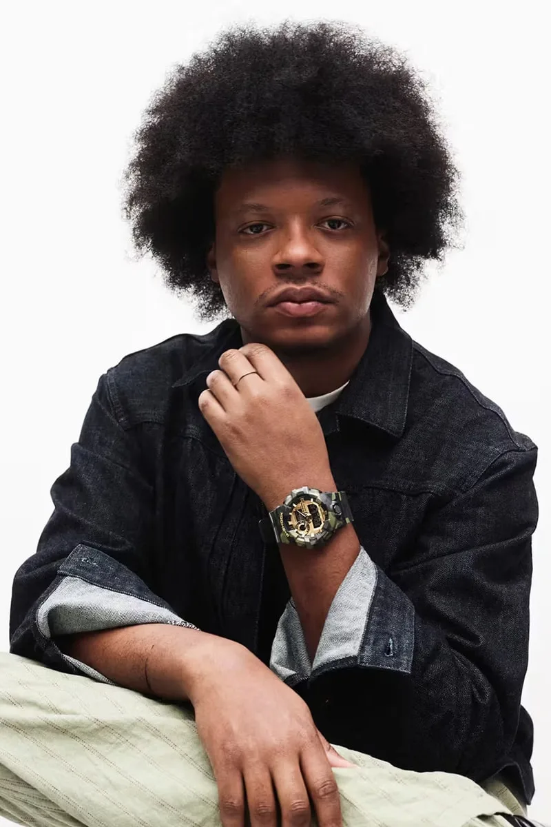 Homme avec afro, veste en jean et montre distinctive.