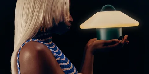 Femme tenant une lampe luminescente contre un fond noir.