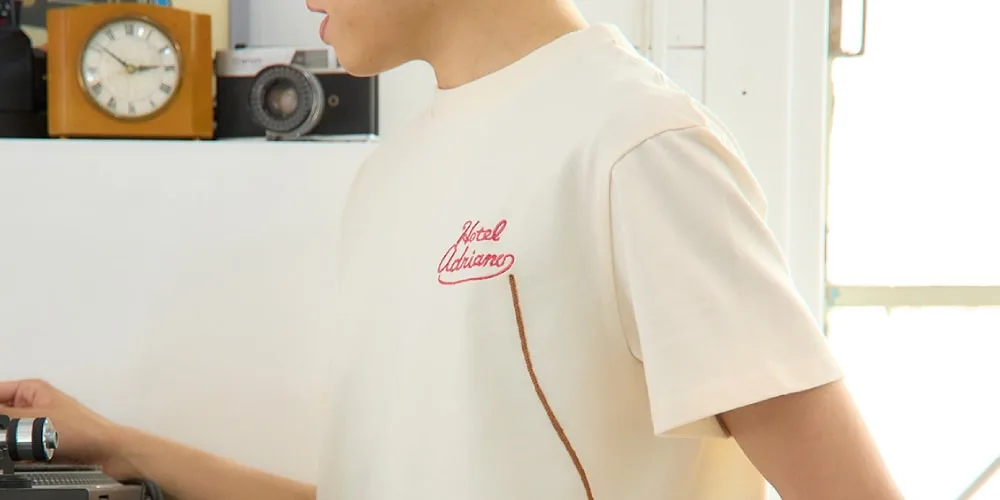 Personne en t-shirt "Hotel Okigama" beige.