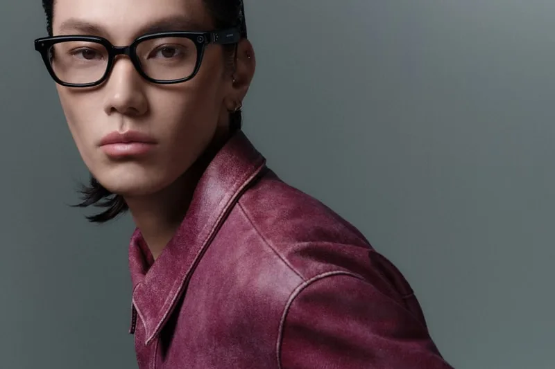 Personne portant des lunettes et une veste en cuir rose, fond gris.
