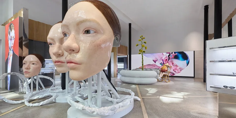 Intérieur moderne avec sculptures de visages géants et mobilier design.