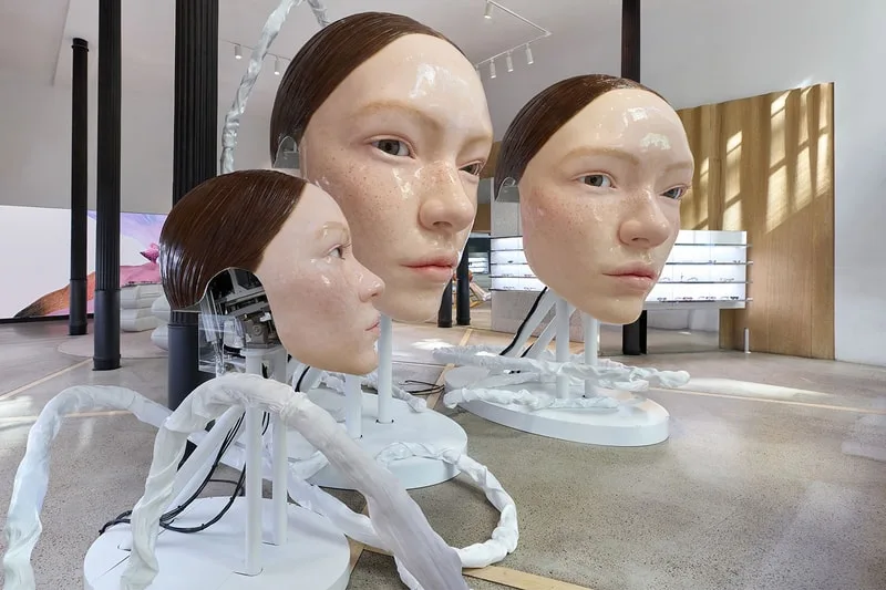 Grandes têtes humanoïdes avec câblage exposé dans une galerie moderne.