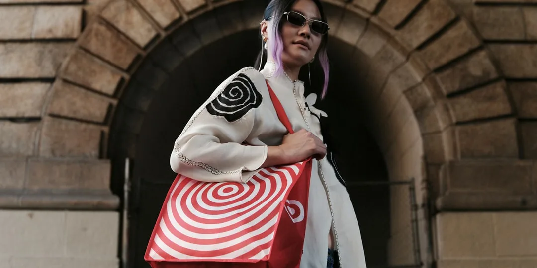 Personne avec un sac à motifs cibles devant une arche en pierre.