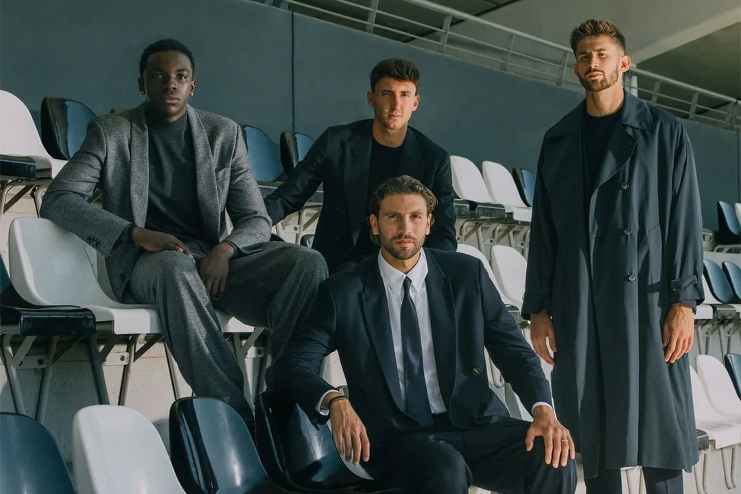 Quatre hommes bien habillés assis et debout dans un stade