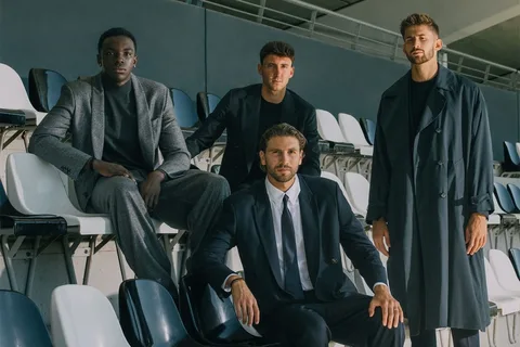 Quatre hommes bien habillés assis et debout dans un stade