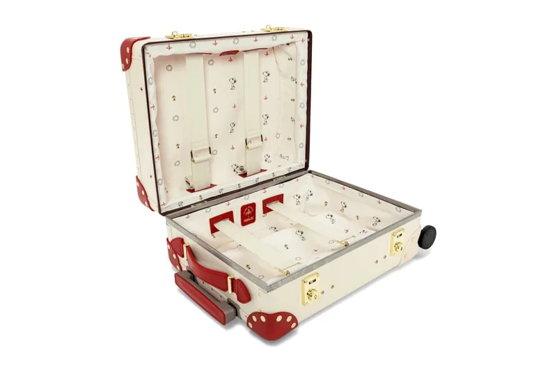 Valise ouverte avec intérieur à motifs rouges et blancs, coins renforcés rouges.