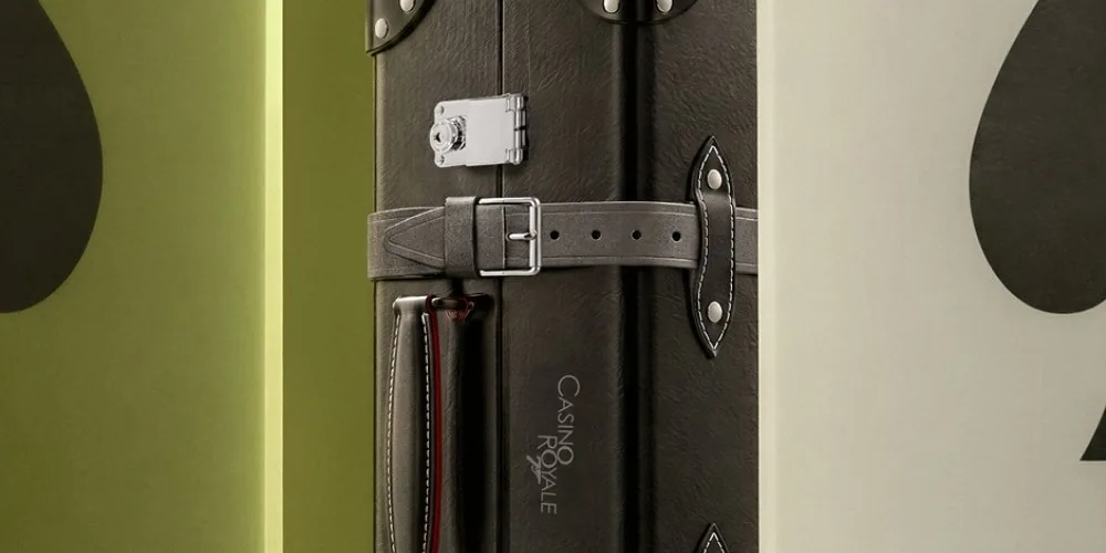 Valise noire avec boucle et inscription Casino Royale sur fond vert.